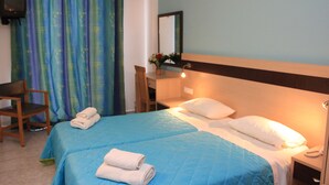 Une chambre d’hôtel avec deux lits, un bureau, une chaise et un téléviseur.