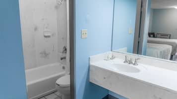 Une salle de bain avec une baignoire blanche, des toilettes et un lavabo avec un miroir.