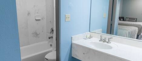 Une salle de bain avec une baignoire blanche, des toilettes et un lavabo avec un miroir.