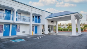 Un motel con puertas azules y un área de estacionamiento techada.