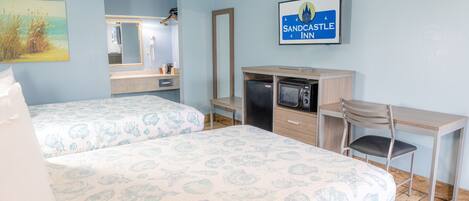 A hotel room with two beds, a desk, a chair, a TV, and a mirror.