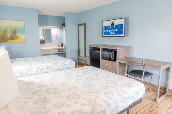 Une chambre d’hôtel avec deux lits, un bureau, une chaise, une télévision et un miroir.
