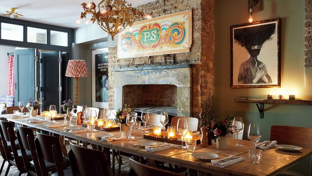 A dining area with a long wooden table set for a meal, a decorative chandelier, a fireplace, and a large framed artwork on the wall. - Artist Residence London (London)