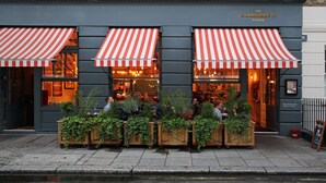 The Cambridge St. Kitchen with outdoor seating and red and white striped awnings. - Artist Residence London (London)