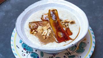 A bowl of oatmeal with bacon and nuts on a patterned plate.