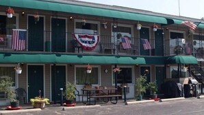 A motel with multiple balconies, American flags, and outdoor seating.
