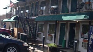 A building with a green awning, a fire escape, and a parked car.