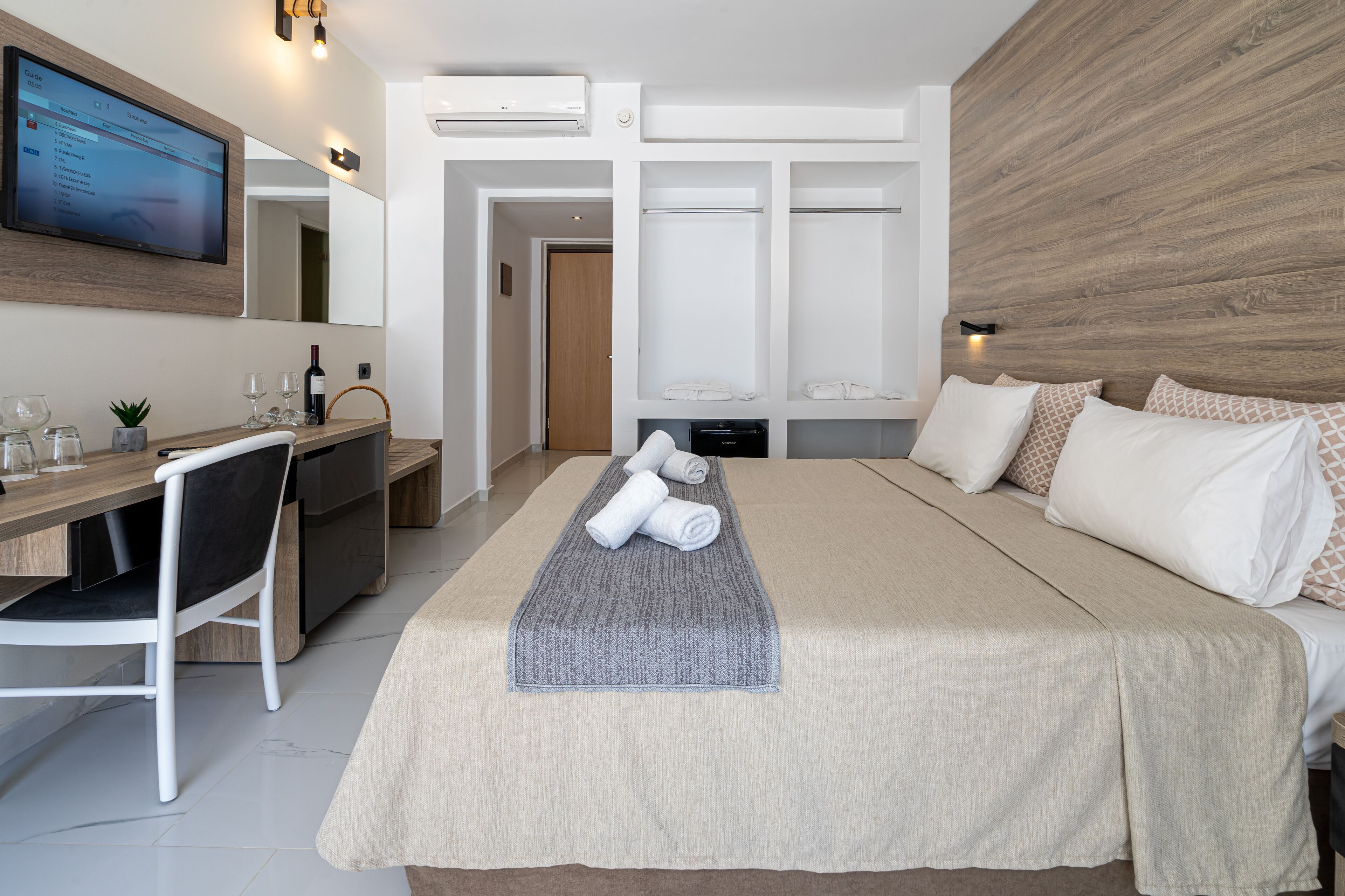 Een moderne hotelkamer met een bed, bureau, televisie en garderobe.