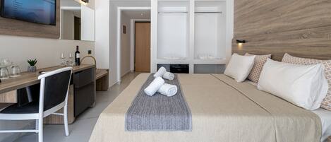 Een moderne hotelkamer met een bed, bureau, televisie en garderobe.