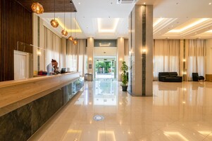 Egy tágas előtér, amelyben található egy recepciós pult, egy ülősarok és egy nagy méretű növény.