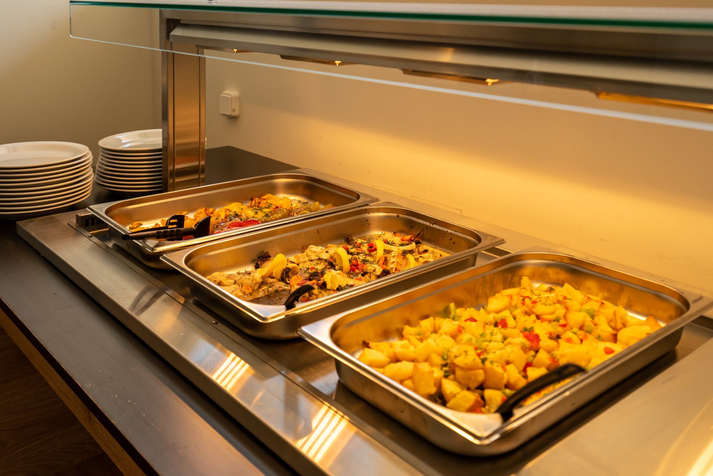 A buffet with various dishes in stainless steel trays, including what appears to be a fruit salad and a casserole.
