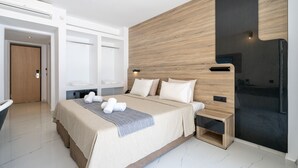 A modern hotel room with a large bed, wooden headboard, and a built-in TV. - Castellum Suites (Rhodes)