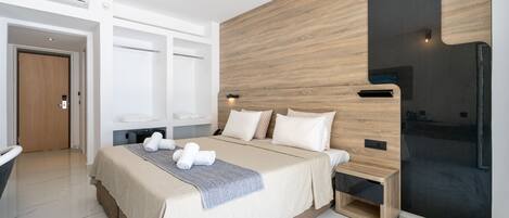 A modern hotel room with a large bed, wooden headboard, and a built-in TV.