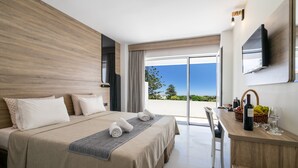 A modern hotel room with a large bed, a desk with a TV, and a balcony with a view. - Castellum Suites (Rhodes)