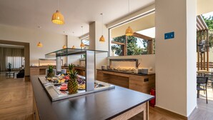 A modern kitchen with a breakfast bar, wooden flooring, pendant lighting, and a view of the outdoors. - Castellum Suites (Rhodes)