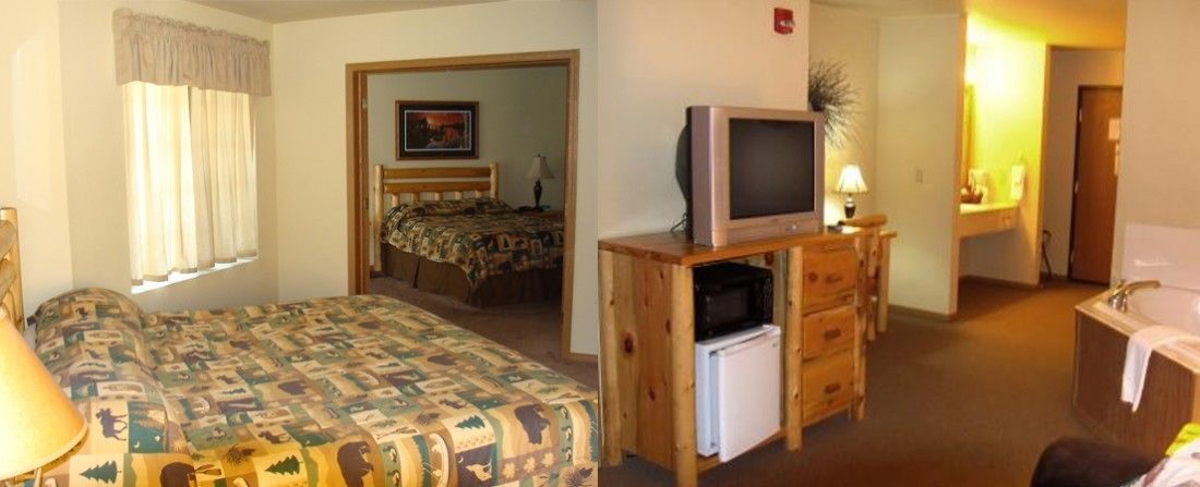 A hotel room with a bed, a television on a wooden stand, a small refrigerator, a bathroom with a sink and mirror, and a door leading to another room.