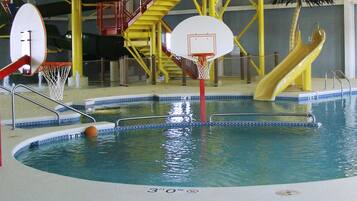 Una piscina interior con aros de baloncesto, un tobogán y un tobogán acuático.