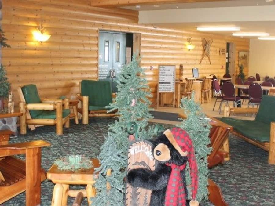 L’intérieur d’un chalet avec des meubles en bois, une cheminée en pierre et des décorations de Noël.