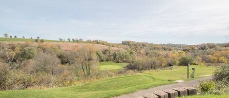 A golf course with a clear path, surrounded by trees and hills.