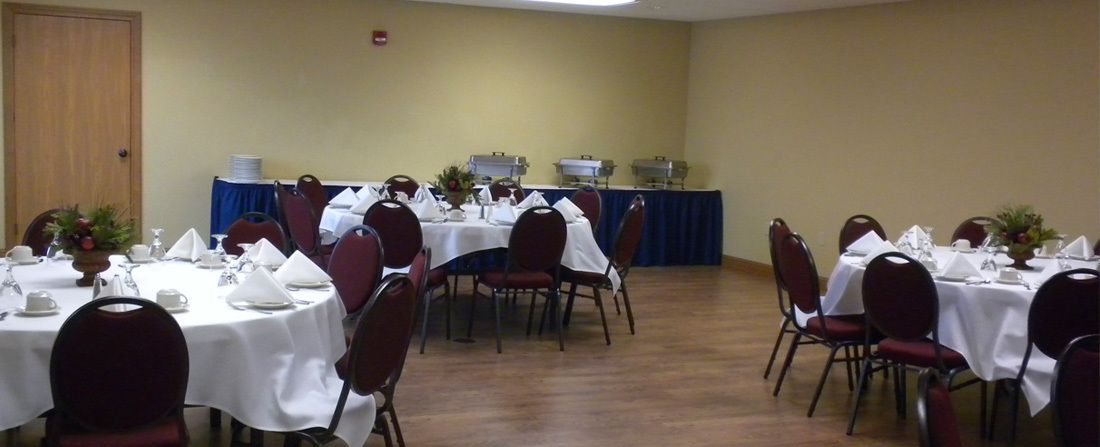 A conference room with round tables, chairs, and a stage with a podium.