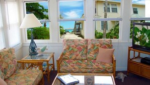 A room with a sofa and armchairs, a small table, and a television. - Sun N Fun Beachfront Vacation Rentals (Indian Shores)