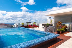 A rooftop pool with a blue mosaic edge, red lounge chairs, and potted plants. - Skyline 24th by Playa Paradise (Playa del Carmen)