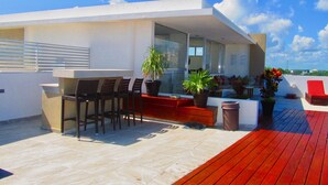 A modern outdoor patio with a dining area, seating, and potted plants.
