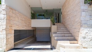 A modern staircase with stone walls and a garage door at the bottom.