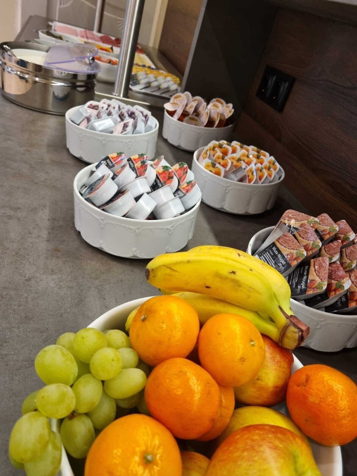 A buffet table with various food items including fruits, pastries, and sandwiches.