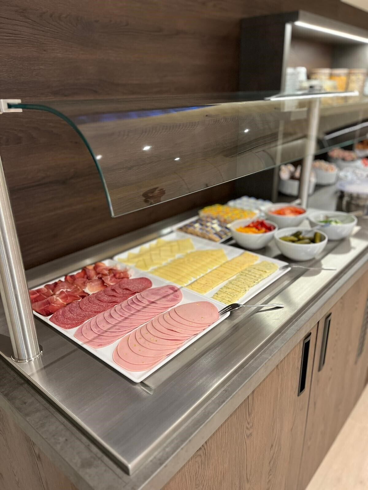 A buffet counter with various food items including sliced meats and cheeses.