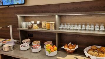 Montaje de bufé con diversos alimentos, como frutas, pasteles y salsas.