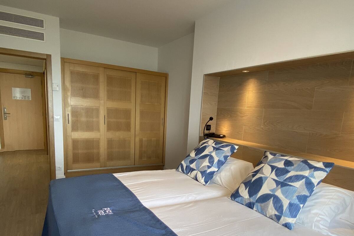 Ein Hotelzimmer mit einem großen Bett, einem Holzschrank und einem Schreibtisch mit Lampe.
