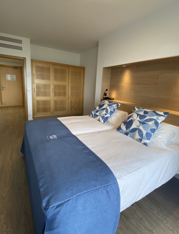 Een hotelkamer met een groot bed, een houten garderobe en een bureau met een lamp.