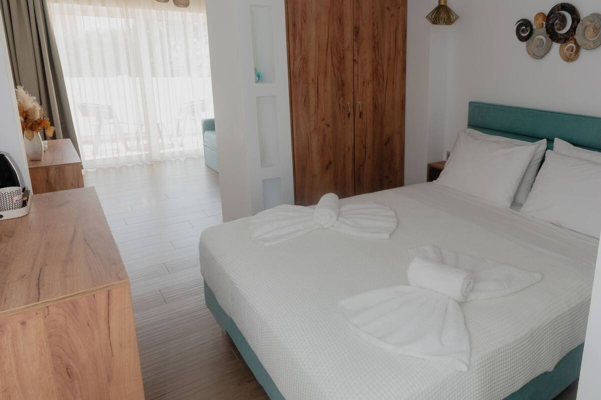 A hotel room with a bed, wooden wardrobe, and a desk.