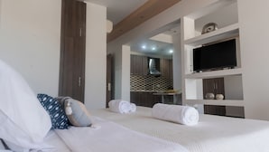 A hotel room with a large bed, a television, and a bathroom visible through an open door. - Sunshine Hotel Lardos (Rhodes)