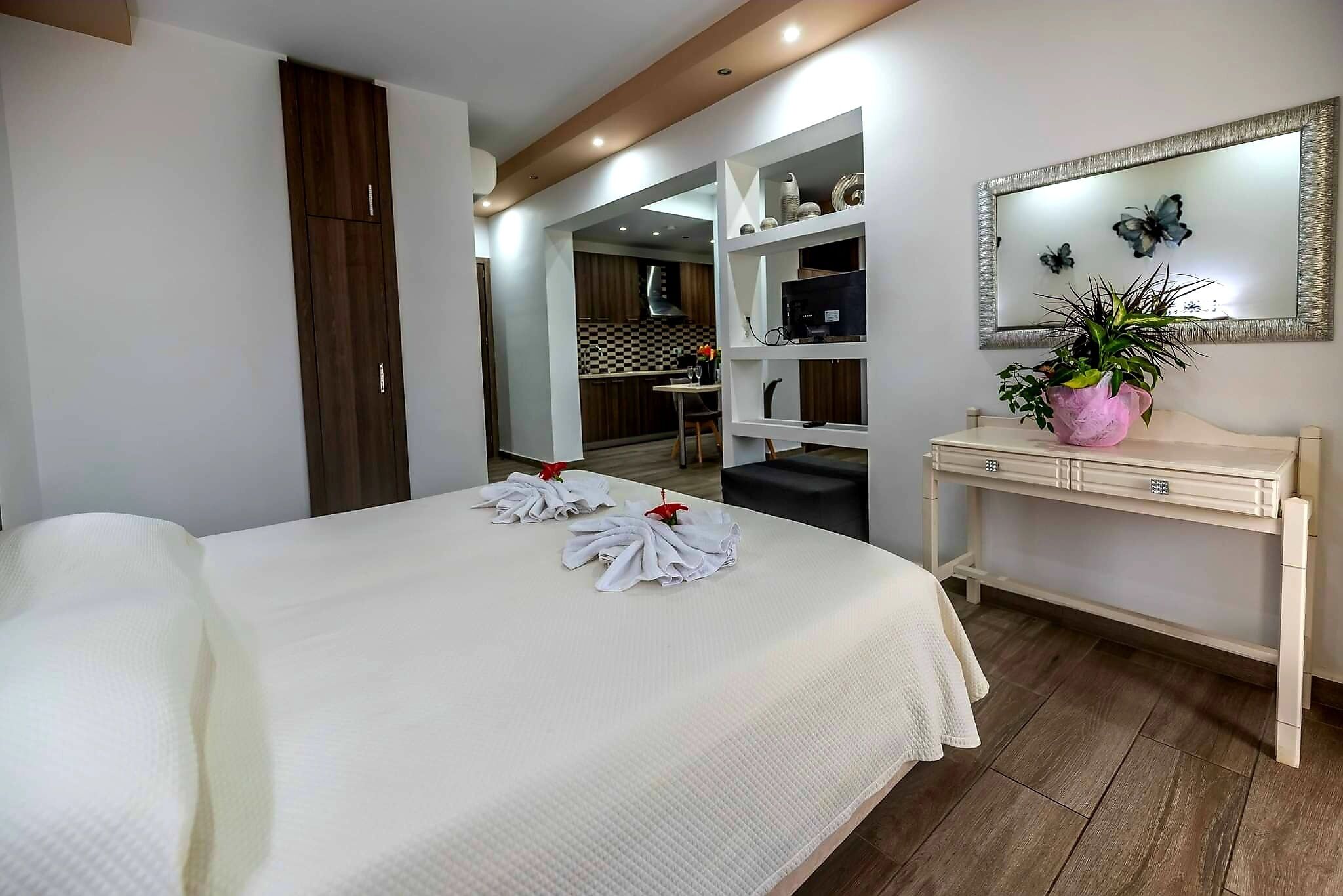 A hotel room with a bed, a desk with a mirror, and a potted plant.