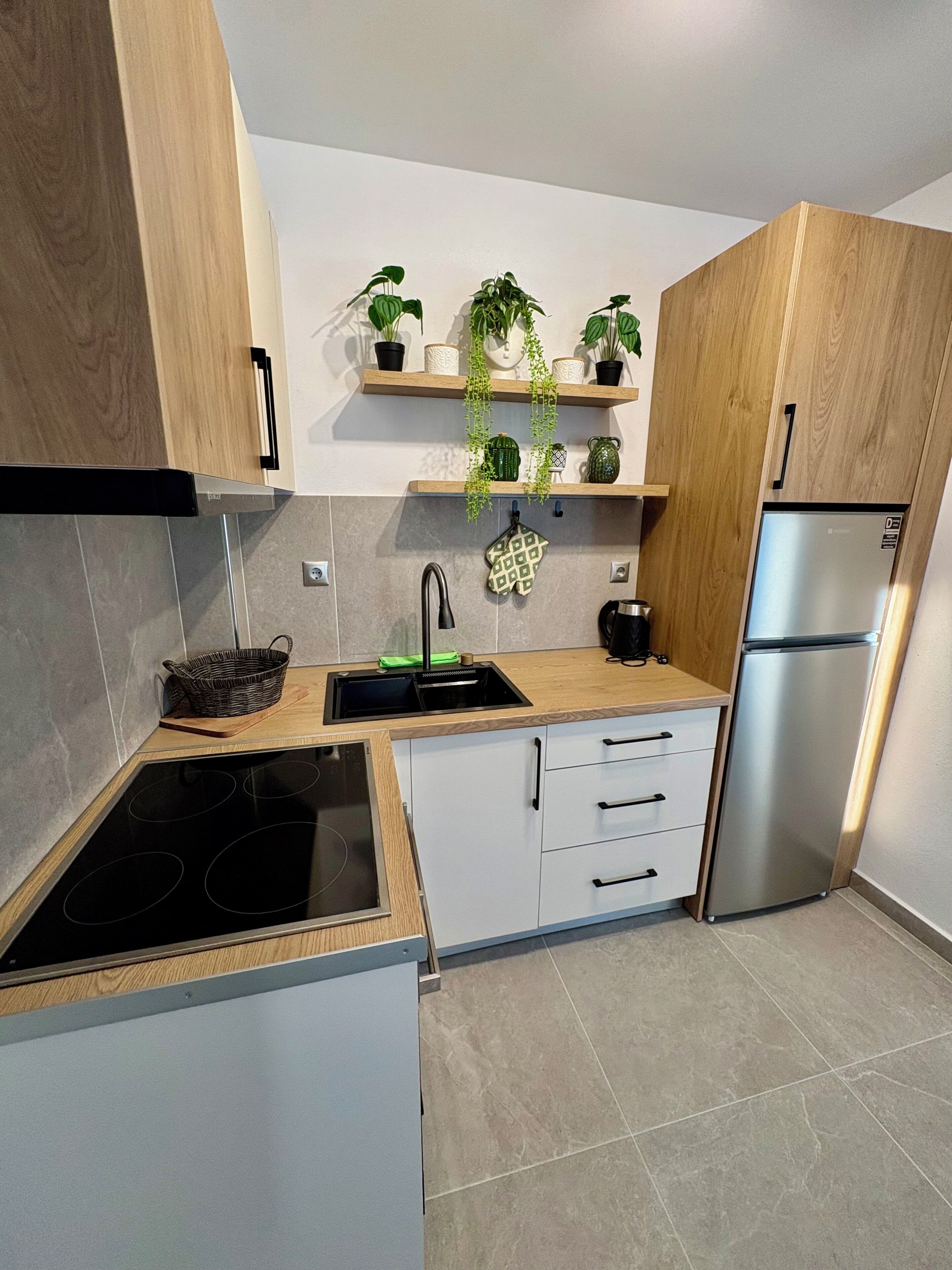 Una cocina moderna con estufa integrada, un lavaplatos, un refrigerador y armarios de madera.