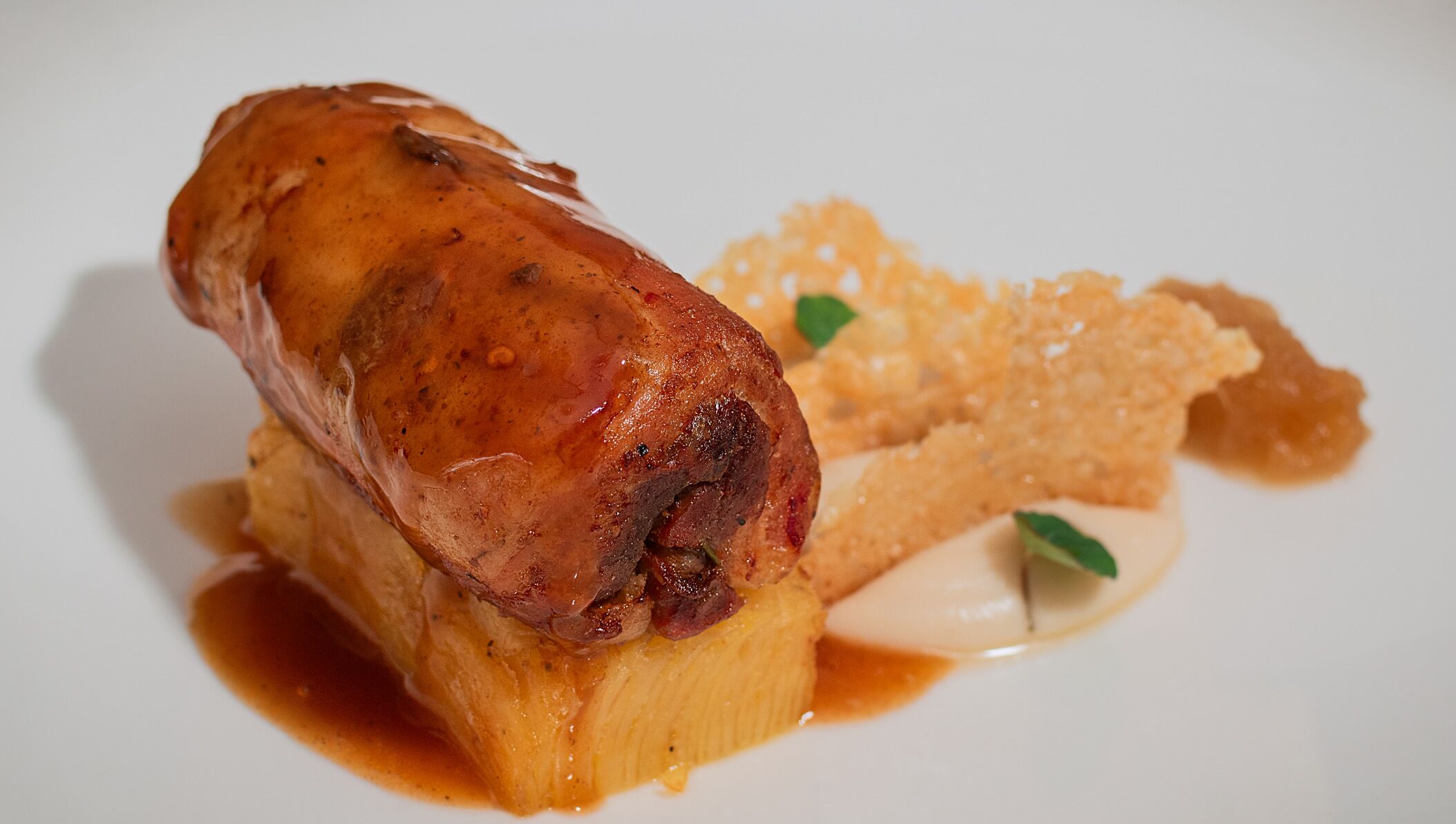 A dish with a roasted meat centerpiece, a side of mashed potatoes, and a creamy sauce.