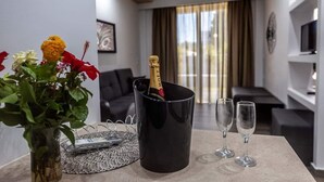 A modern living room with a black coffee table, a vase with flowers, a champagne bottle in a black mug, and two wine glasses. - Sunshine Hotel Lardos (Rhodes)