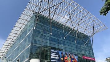 Un edificio moderno de vidrio con un gran anuncio que promociona un evento.