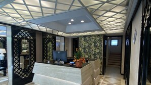 A reception area with a modern design, featuring a geometric ceiling, a reception desk, and a patterned floor.