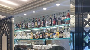 A bar area with shelves of liquor bottles, a coffee machine, and a variety of glasses.