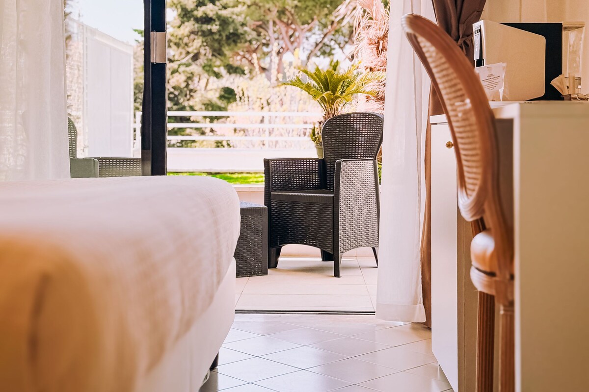 A hotel room with a bed, a desk with a chair, and a view of the outdoors.
