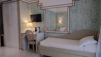 A bedroom with a bed, a desk with a chair, a television, and a mirror.