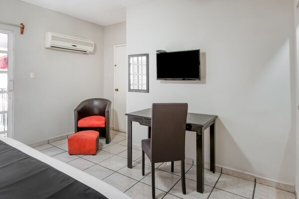 A small, clean room with a bed, a desk, a chair, and a TV.