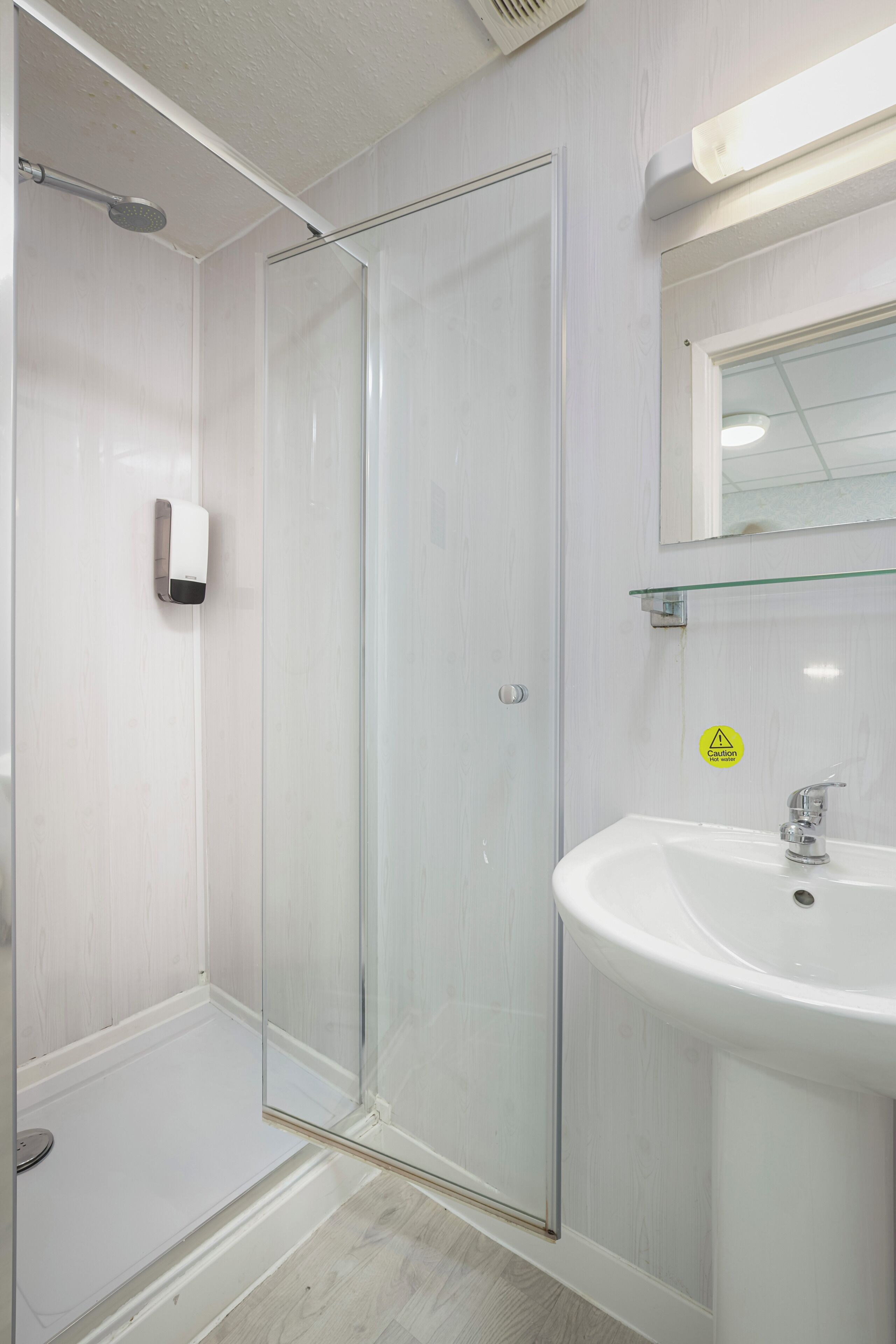 A bathroom with a glass shower enclosure, a white sink, and a mirror above the sink.