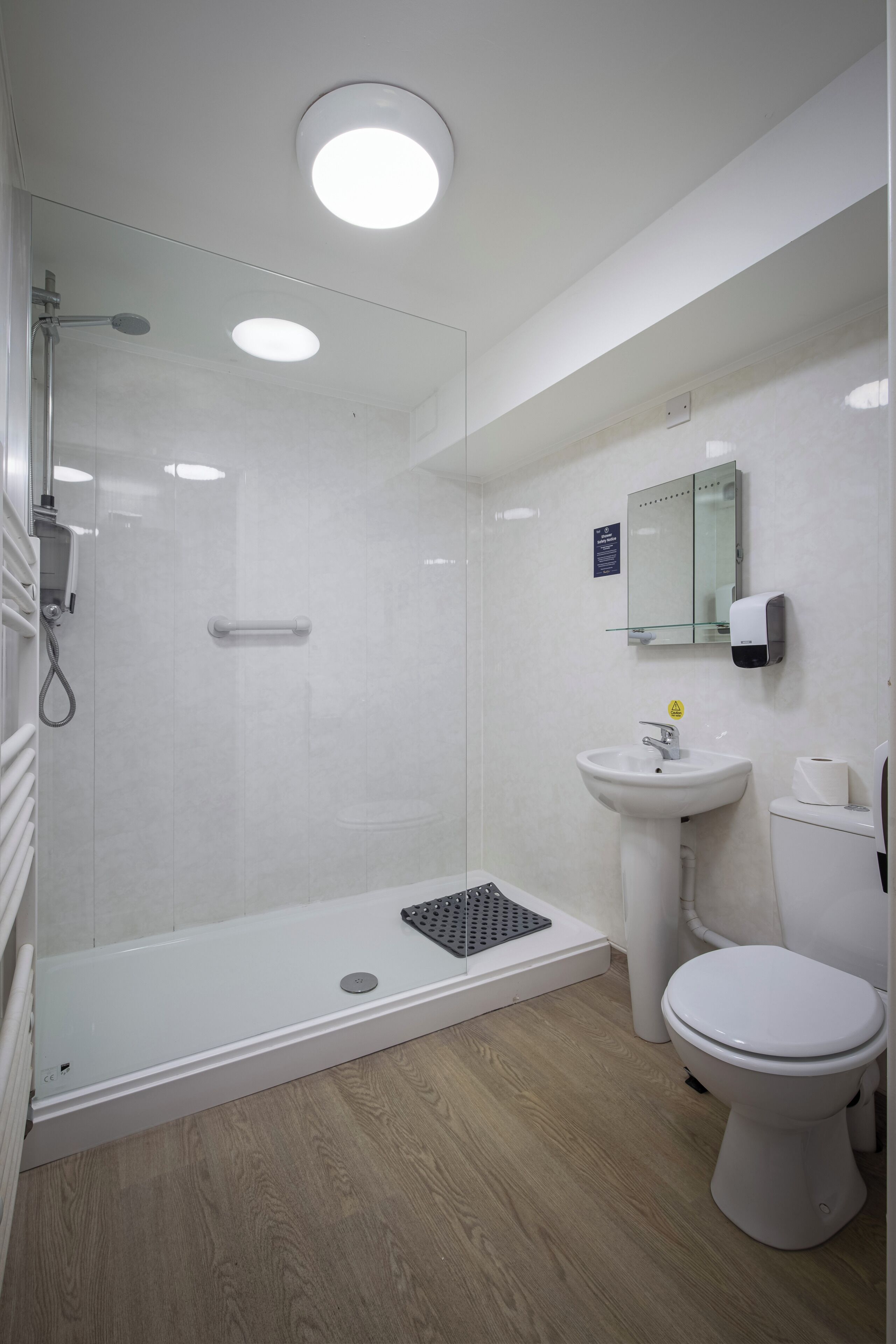 Un baño moderno con ducha, lavamanos, inodoro y espejo.