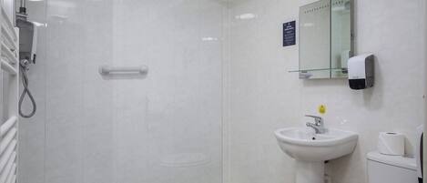 Un baño moderno con ducha, lavamanos, inodoro y espejo.