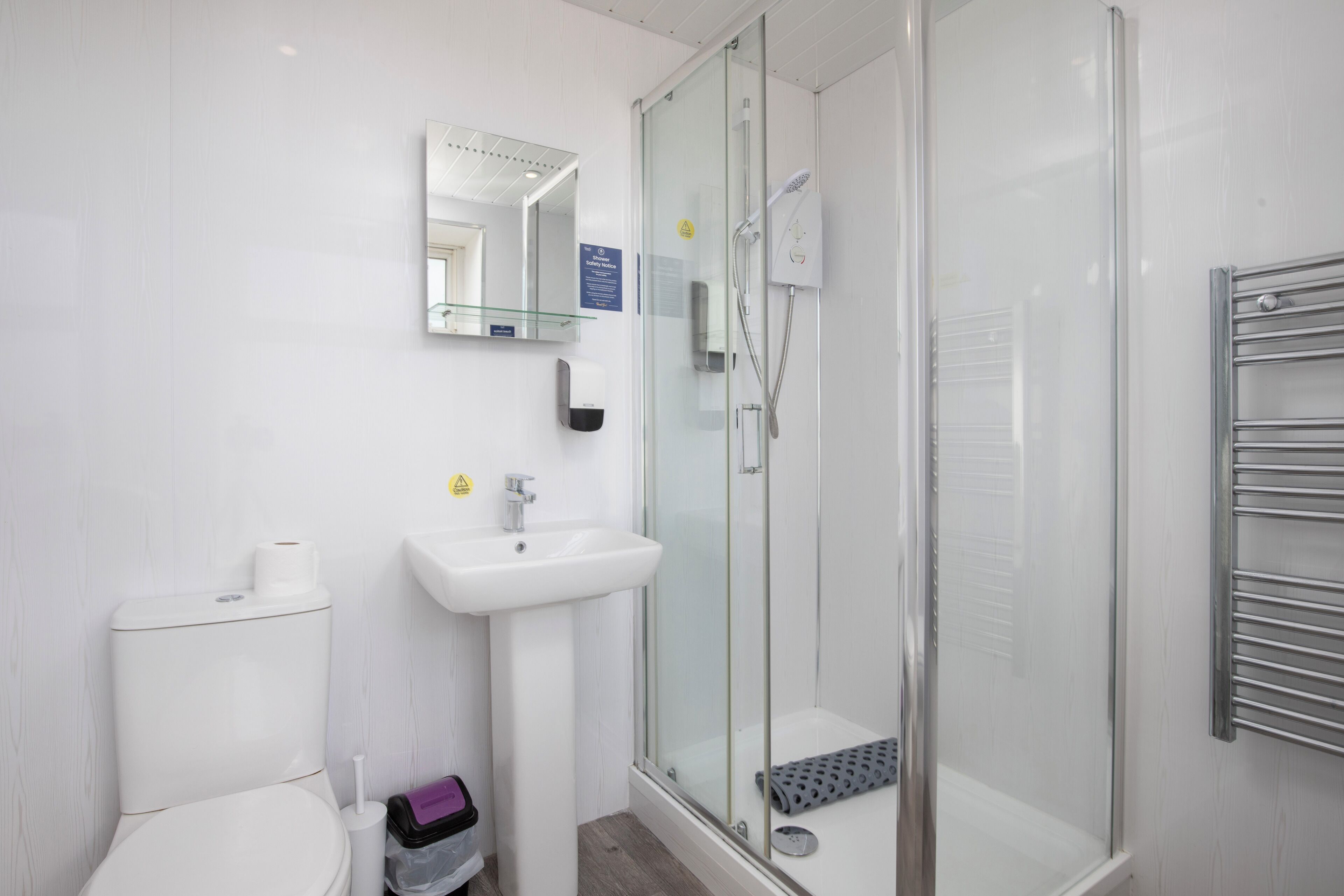 A bathroom with a toilet, sink, and glass-enclosed shower.
