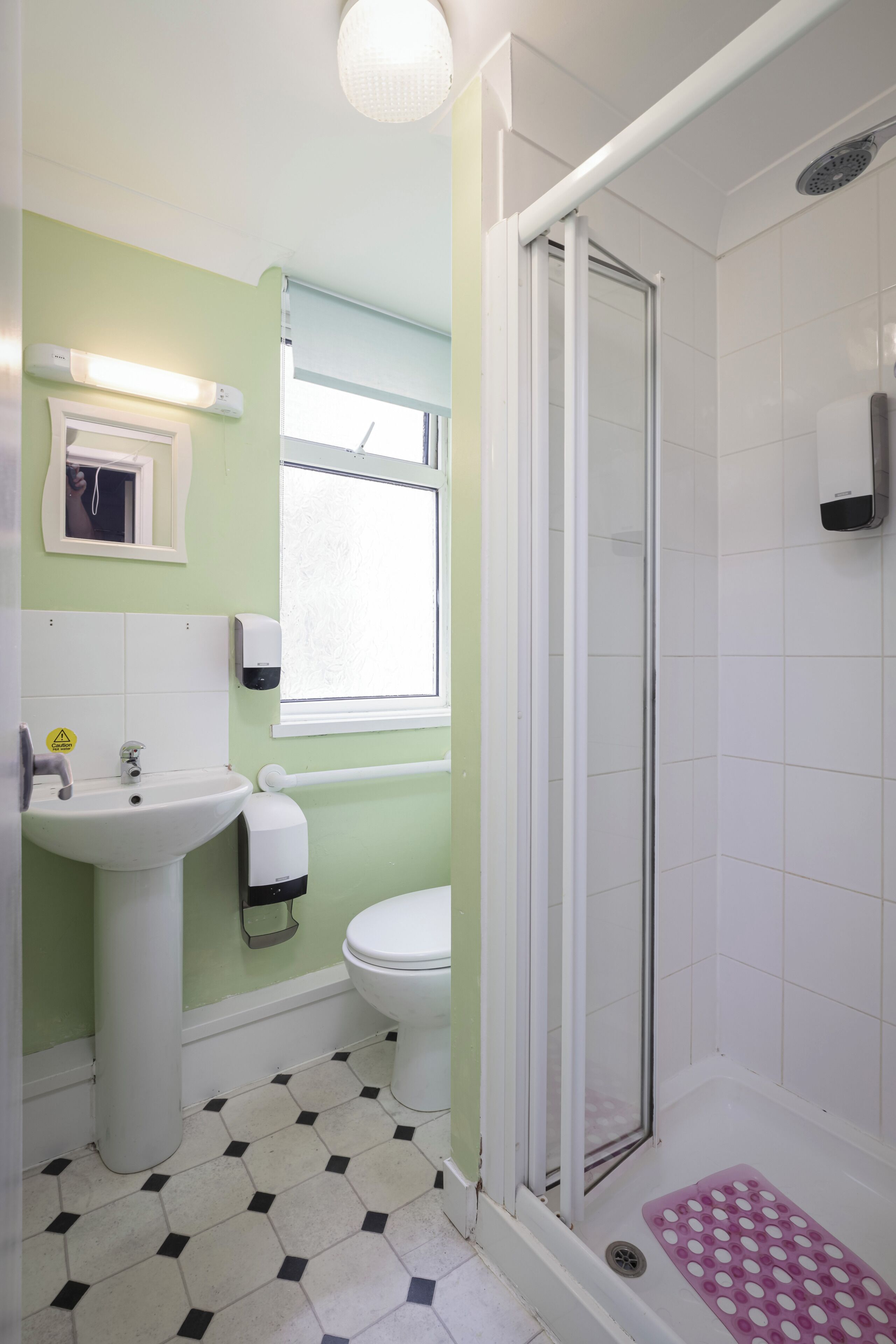 A bathroom with a sink, toilet, shower, and a window.